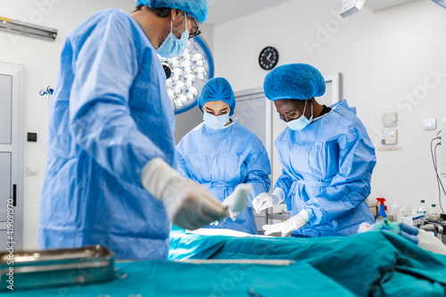 Operating Room of Surgical Table with Instruments, Assistant Picks up Instruments for Surgeons During Operation. Surgery in Progress. Professional Medical Doctors Performing Surgery.