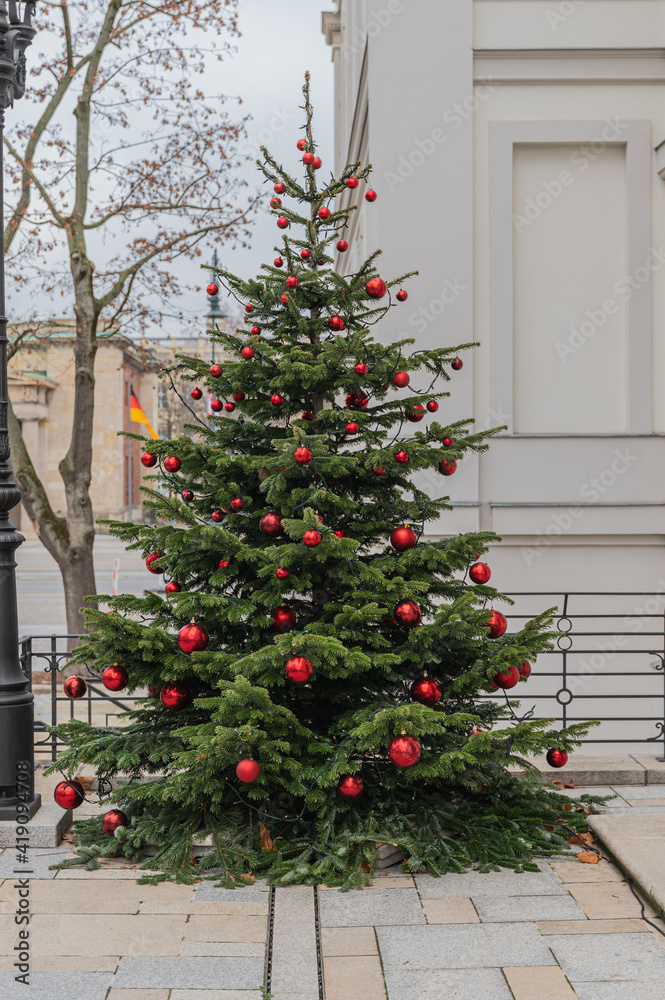 In rot geschmückter Weihnachtsbaum im Freien vor einem Gebäude In rot geschmückter Weihnachtsbaum im Freien vor einem Gebäude