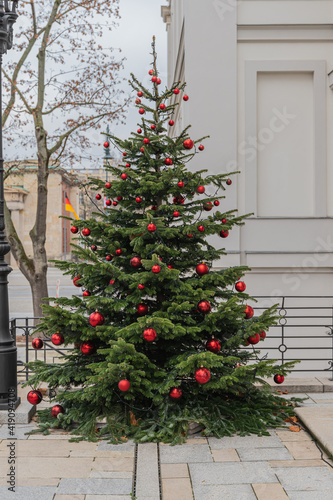 In rot geschmückter Weihnachtsbaum im Freien vor einem Gebäude