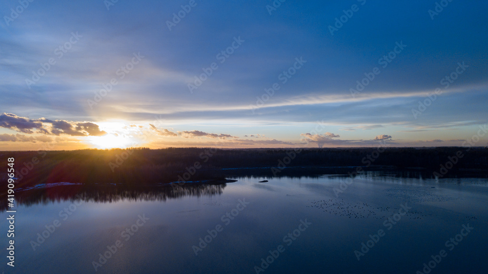 Aerial view of a beautiful and dramatic sunset over a forest lake reflected in the water, landscape drone shot. Blakheide, Beerse, Belgium. High quality photo
