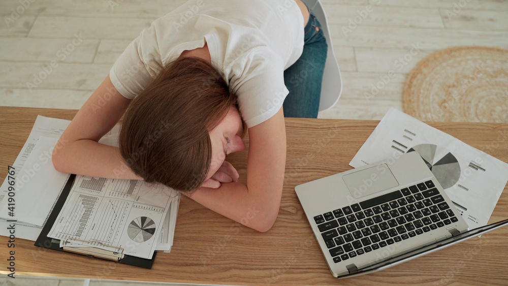 Young tired woman sleeping at her office desk near the laptop Young tired woman sleeping at her office desk near the laptop