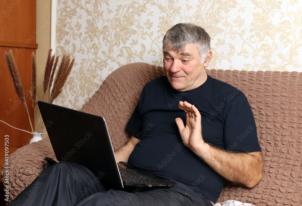 Relaxed man smiling while sitting on sofa with laptop