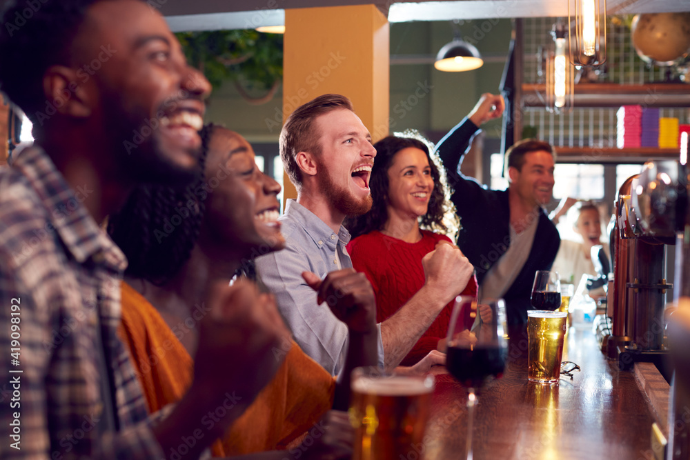 Group Of Excited Customers In Sports Bar Watching Sporting Event On Television Group Of Excited Customers In Sports Bar Watching Sporting Event On Television