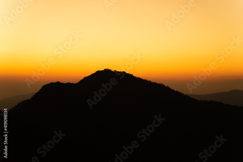 backlit silhouette photo of mountain peaks the background is the light from the setting sun.
