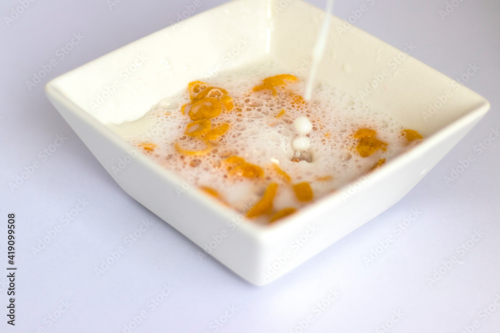 Milk being poured in to the white bowl with cereal in it. Food Milk being poured in to the white bowl with cereal in it. Food