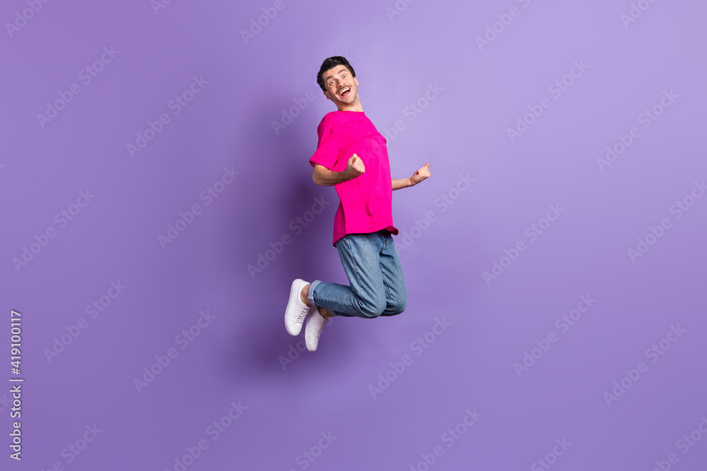 Full length photo of astonished person jumping fists up celebrate have fun isolated on violet color background