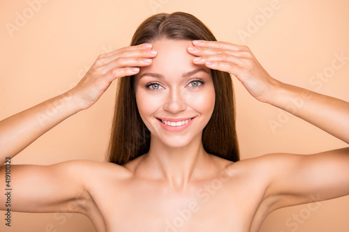 Photo of young girl happy positive smile hands touch forehead cleansing skin isolated over beige color background