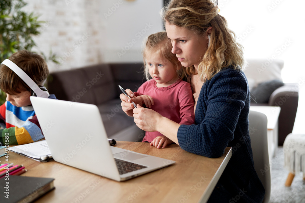 Mother during home office with little daughter on her lap Mother during home office with little daughter on her lap