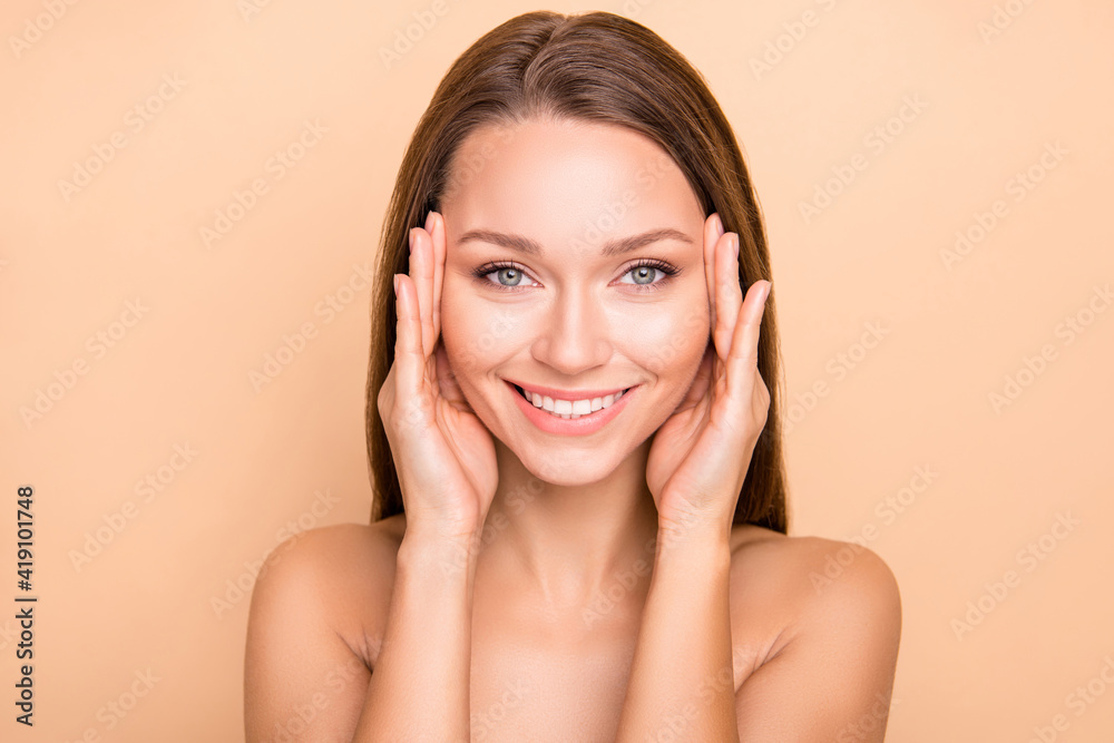Portrait of attractive cheerful girl touching perfect facial oval therapy isolated over beige pastel color background Portrait of attractive cheerful girl touching perfect facial oval therapy isolated over beige pastel color background