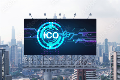 ICO hologram icon on billboard over panorama city view of Kuala Lumpur at day time. KL is the hub of blockchain projects in Malaysia, Asia. The concept of initial coin offering, decentralized finance