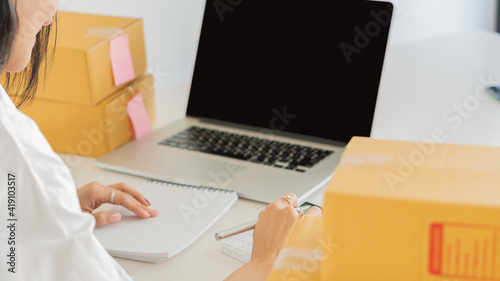 Small Business Startup Freelance SME Entrepreneurs Beautiful Asian Young Women Working at Home with Box, Smartphone, Laptop on the Table with Online Sales, Marketing, Packaging, SME Shipping, Ecommerc © ArLawKa