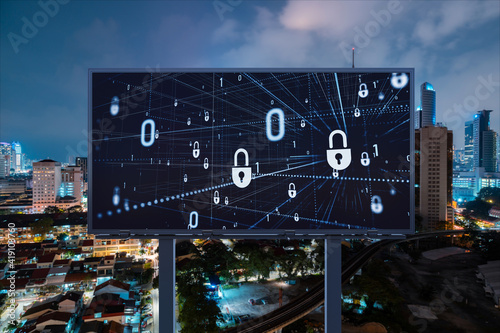 Padlock icon hologram on road billboard over panorama city view of Kuala Lumpur at night to protect business, Malaysia, Asia. The concept of information security shields.