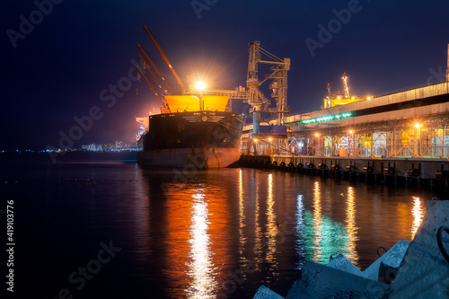 a large ship stands at night in the port for loading