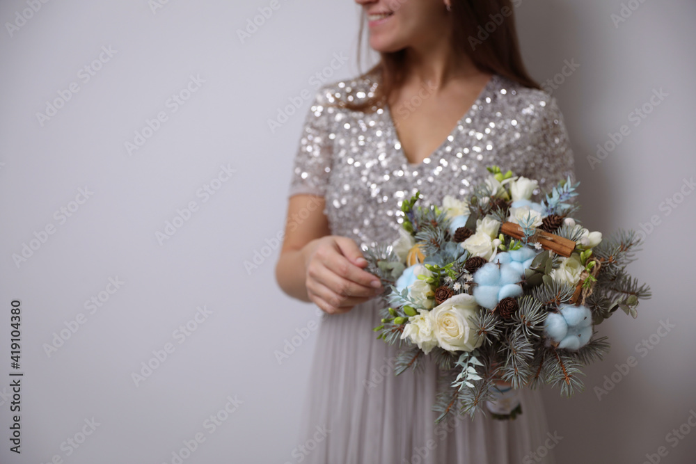 Bride holding beautiful winter wedding bouquet on light grey background, closeup. Space for text Bride holding beautiful winter wedding bouquet on light grey background, closeup. Space for text