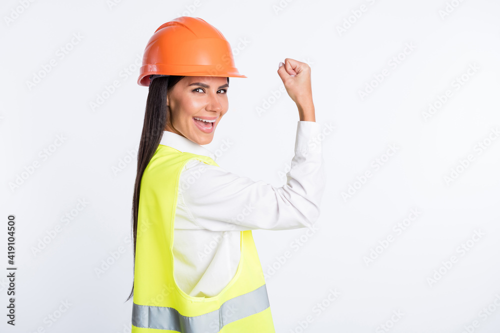 Photo of excited worker lady raise arm show muscle wear helmet shirt vest isolated white color background