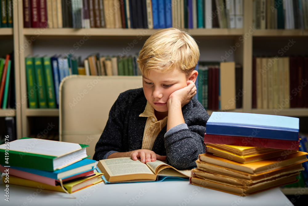 child boy under mental pressure while reading books preparing examinations, in library . child boy under mental pressure while reading books preparing examinations, in library .