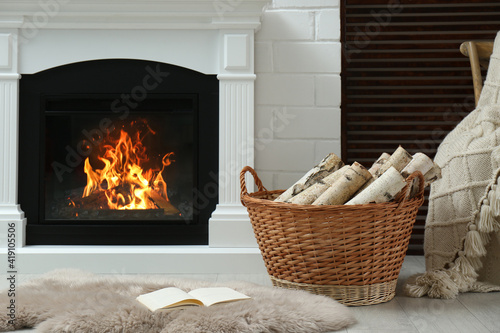 Firewood in wicker basket near fireplace indoors