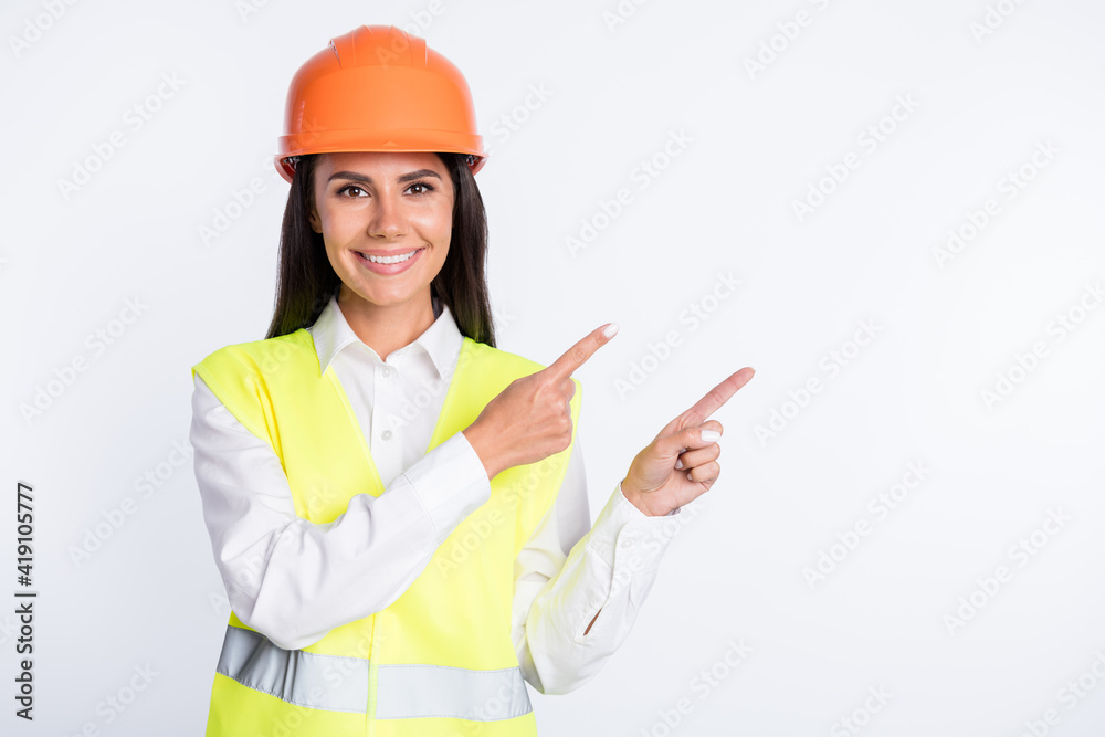 Photo of adviser lady direct fingers empty space toothy smile wear helmet shirt vest isolated white color background