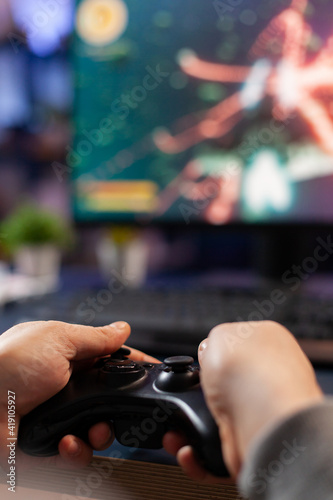 Closeup of competitive player holding joystick playing space shooter video games at powerful computer late night. Professional gamer using controller for online championship sitting on gamining chair