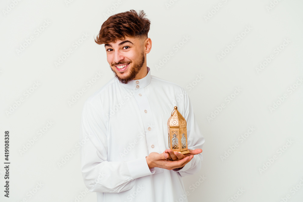 Young Moroccan man wearing a typical arab clothes holding a ramadan lamp isolated on white background laughing and having fun. Young Moroccan man wearing a typical arab clothes holding a ramadan lamp isolated on white background laughing and having fun.