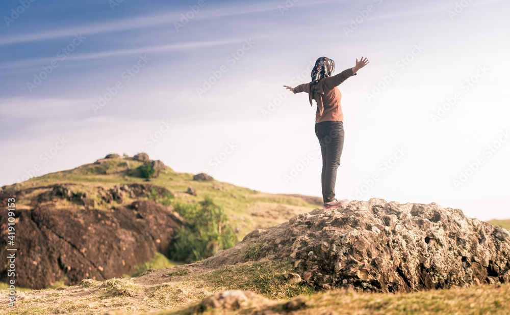 A woman enjoying the view on a tropical savanna of merese hills, lombok island. before sunset. https://www.lombokjourney.com