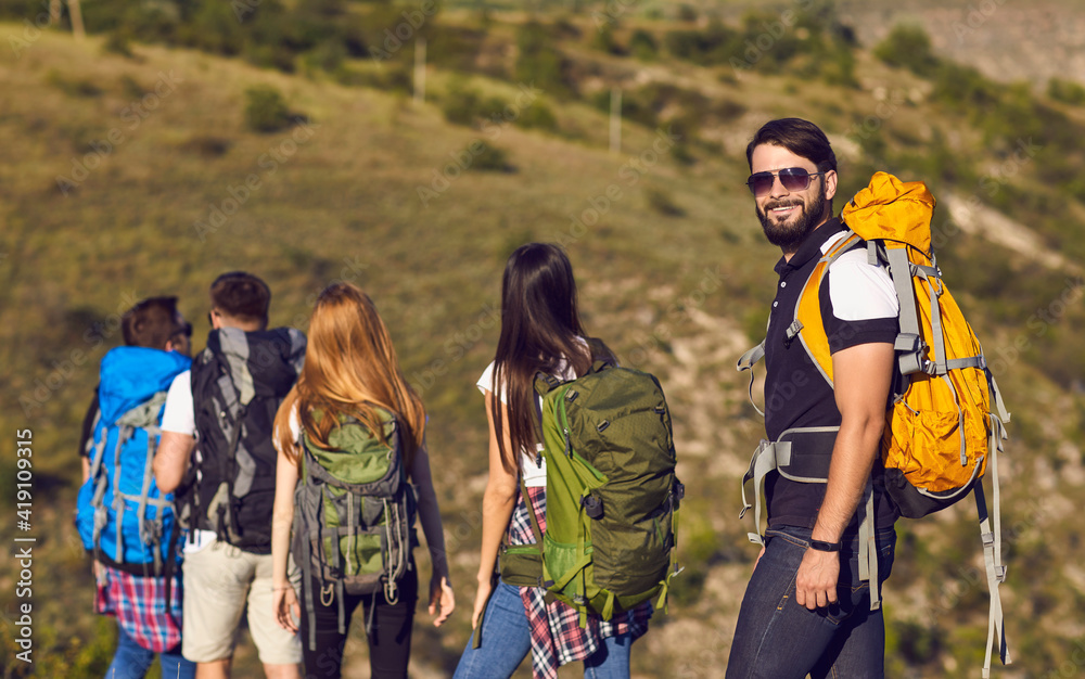 Group of hikers with backpacks walking through the beautiful mountains.