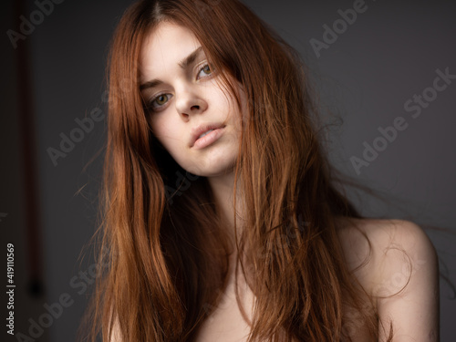 Portrait of beautiful woman on gray background bare shoulders close-up cropped view