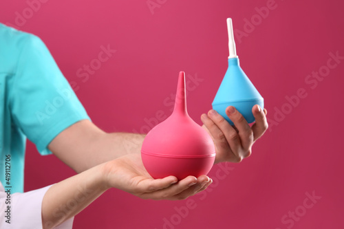 Photos People holding enemas on pink background, closeup