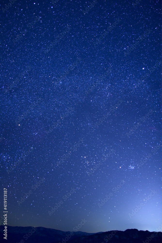 Obraz premium 山のシルエットと満天の星空。