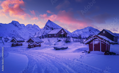 Scenic image of mountain landscape during sunset. Colorful sky over the Snowcowered mountain and frozen fjord under vivid pink sunlight. Stunning nature background. Lofoten islands. North Norway.