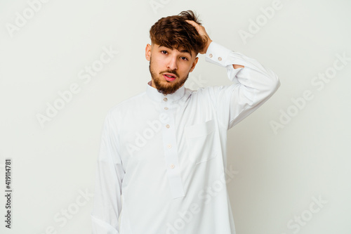 Young Moroccan man wearing a typical arab clothes isolated on white background tired and very sleepy keeping hand on head. © Asier