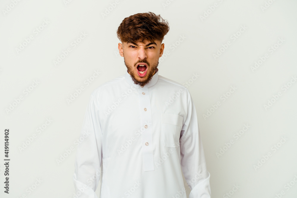 Young Moroccan man wearing a typical arab clothes isolated on white background screaming very angry and aggressive.
