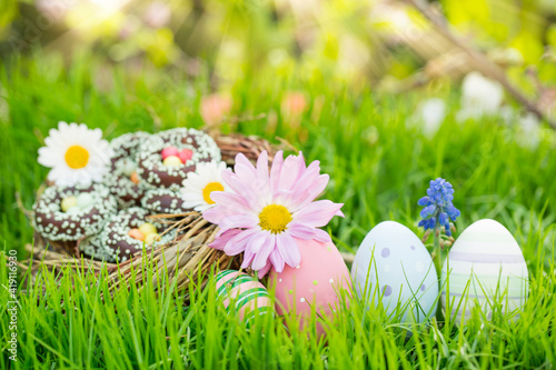 Easter basket with colorful easter eggs in the meadow in spring landscape in the garden. Trees in background and blur. Postcard. photo