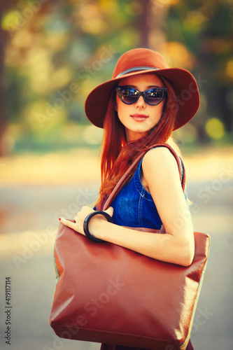 Beautiful redhead girl with bag in the park.
