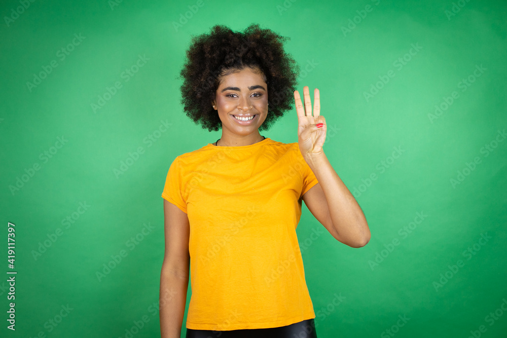 African american woman wearing orange casual shirt over green background showing and pointing up with fingers number three while smiling confident and happy African american woman wearing orange casual shirt over green background showing and pointing up with fingers number three while smiling confident and happy