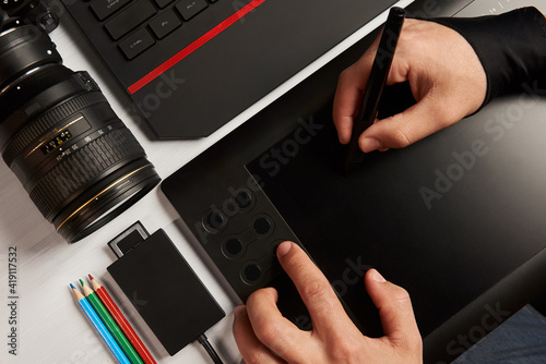 top view of photographer's desktop. hands working on a graphics tablet 