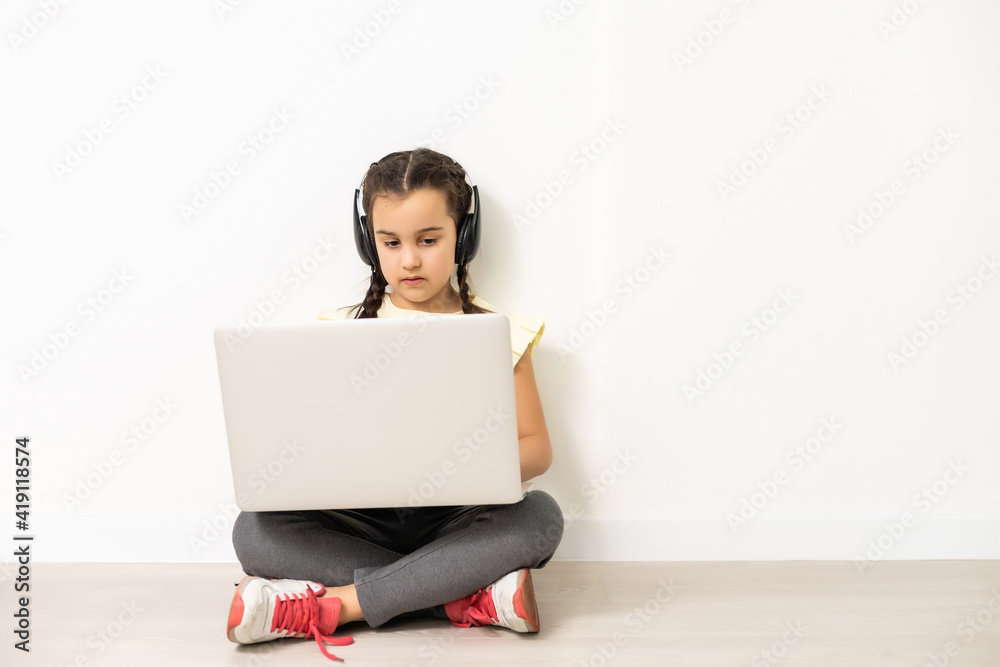 Full length little girl sitting on the floor, laptop computer screen, isolated over white Full length little girl sitting on the floor, laptop computer screen, isolated over white