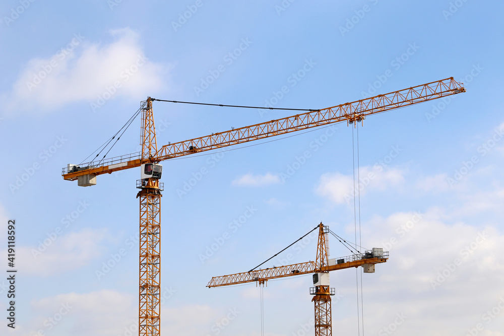 Construction cranes on blue sky and white clouds background. Housing construction in city