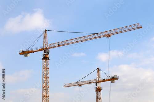 Construction cranes on blue sky and white clouds background. Housing construction in city