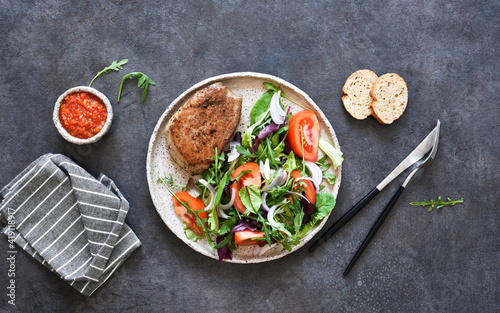 Grilled beef steak medium with mix salad and tomatoes on a black concrete background.