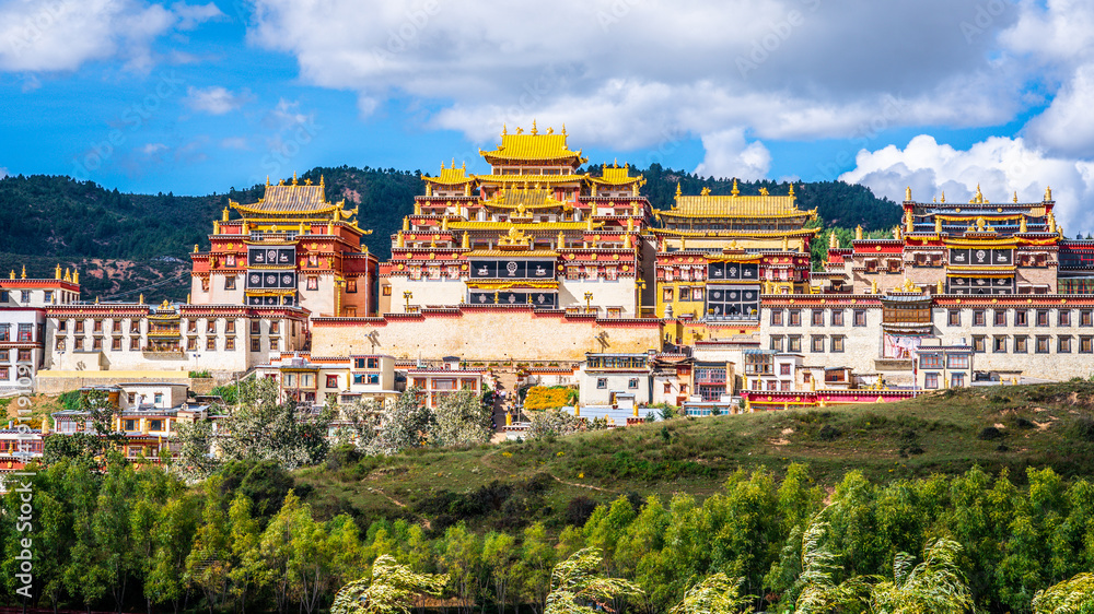 Ganden Sumtseling monastery main buildings scenic view with golden roofs surrounded by green nature Shangri-La Yunnan China
