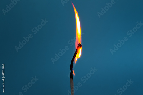 burning match on a blue background.  source of fire.  Beautiful fiery silhouette from a match