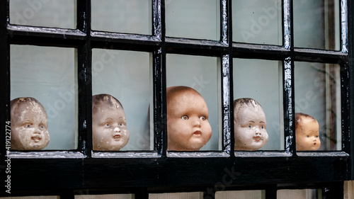 Collection of old doll heads in a window photo