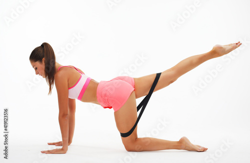 Resistance band fitness. Young woman doing leg workout donkey kick floor exercises with strap elastic.