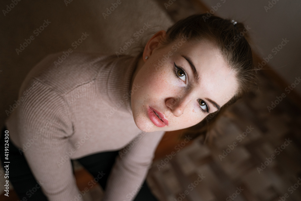 close-up portrait of a girl with freckles on her face looking at the camera, view from the top