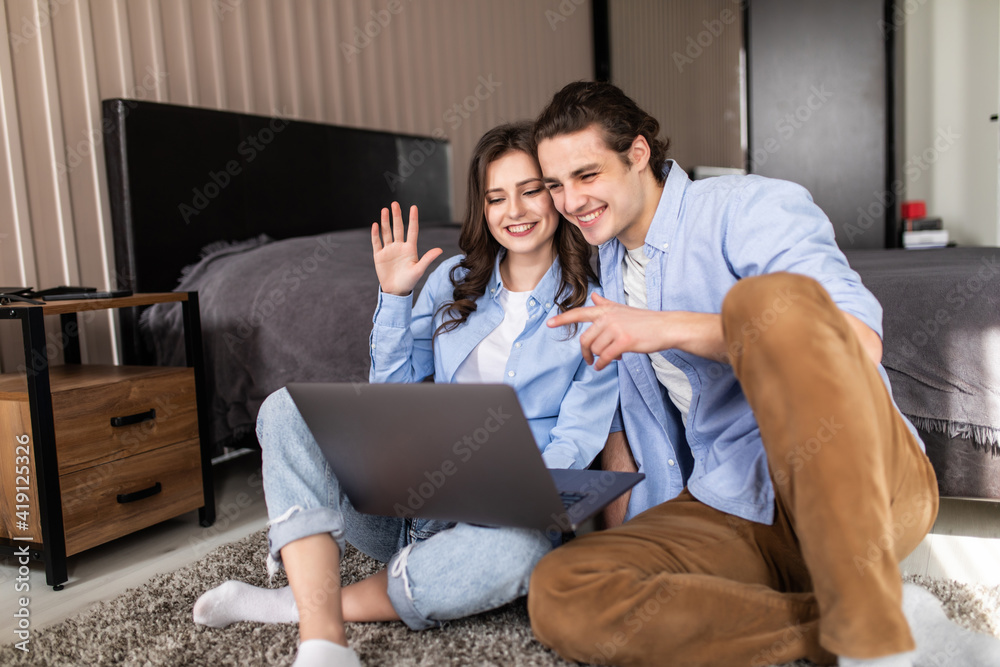 Young couple video chatting sitting on floor at home in bedroom Young couple video chatting sitting on floor at home in bedroom