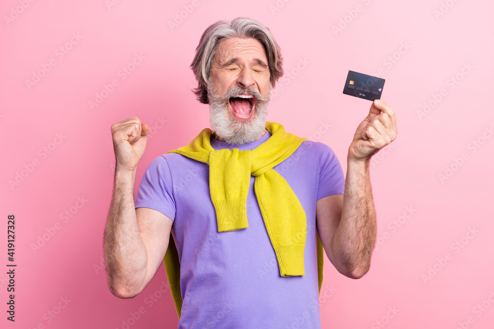 Portrait of attractive cheerful overjoyed gray-haired man holding bank card having fun isolated on pink pastel color background Portrait of attractive cheerful overjoyed gray-haired man holding bank card having fun isolated on pink pastel color background