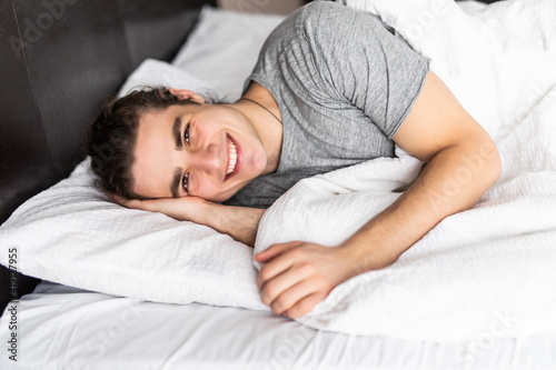 Side view of young man sleeping in bed