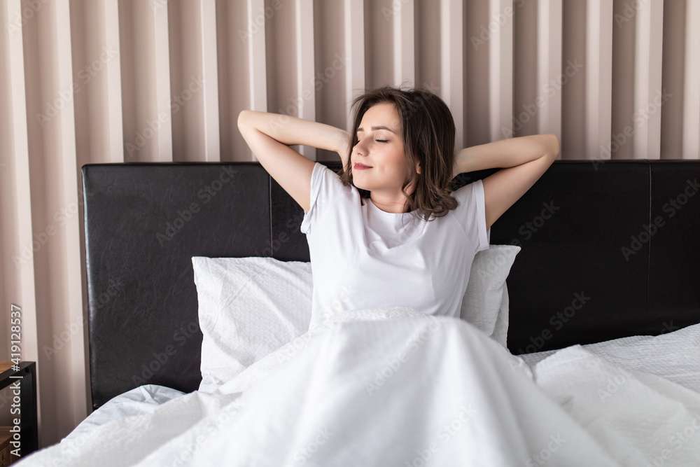 Happy young woman stretching hands on the bed at home Happy young woman stretching hands on the bed at home