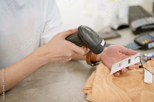 Obraz na płótnie women holding Bar code Scanner to scanning price on T-shirt in her shop w salonie